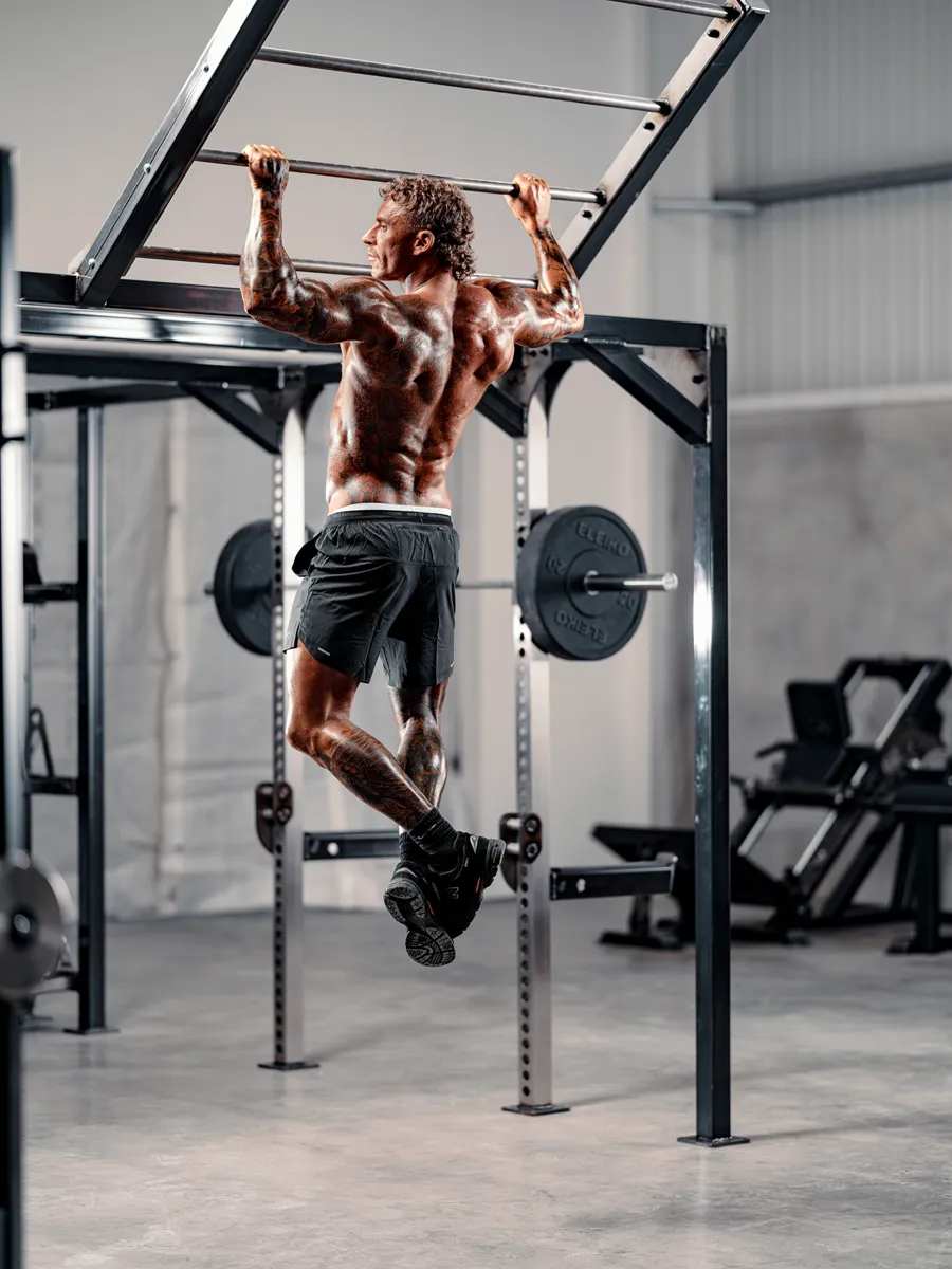 Jack Shipley performing a pull-up on the monkey bar rig at Bailey Studio
